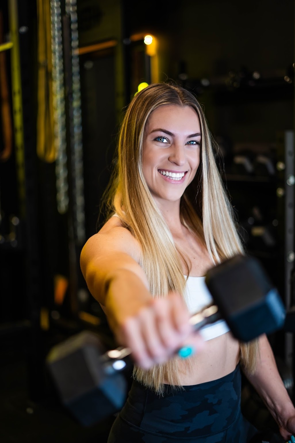 Carly G looking into the camera, holding an arm weight
